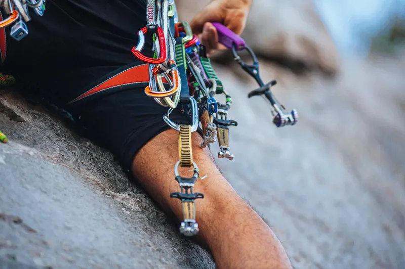 A rock climber's gear attached to their harness, showcasing colorful carabiners and equipment.